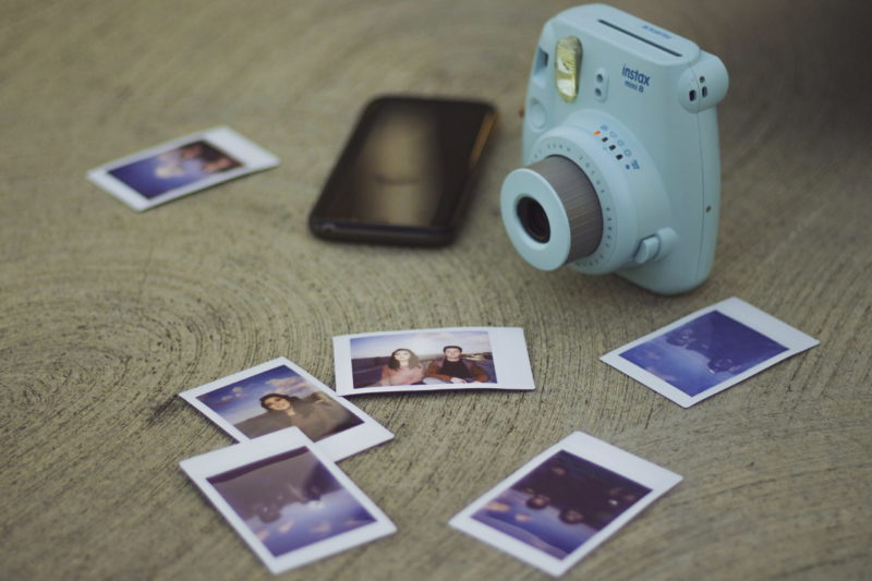 fotos polaroid con cámara fujifilm sobre una mesa de madera